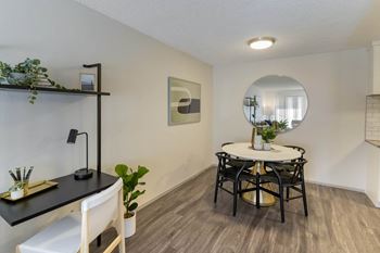 A dining room with a table and chairs and a mirror